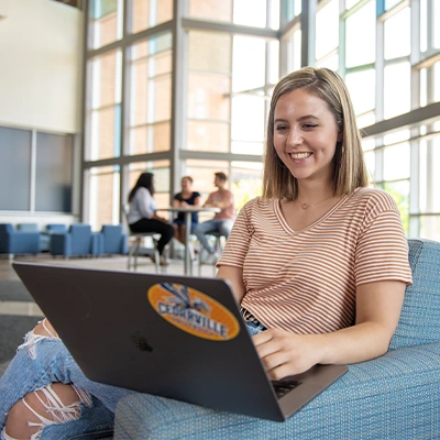 Female student studying on laptop in building