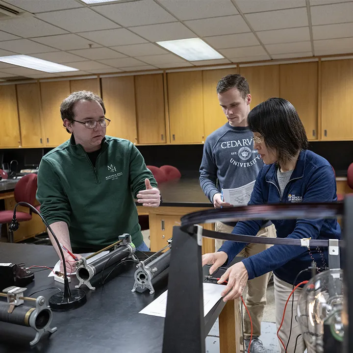 Cedarville University engineering students and professor conducting a hands-on physics lab experiment with electrical equipment in a campus classroom.