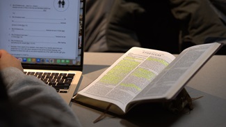 student studying with laptop and open Bible