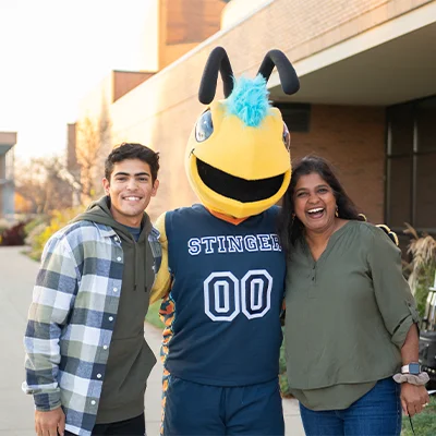 Visiting student and mom smiling with Stinger mascot.