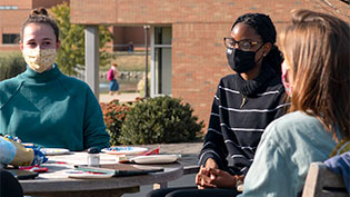 Female students sitting at a table outside.