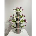 Elegant ceramic piece featuring four stacked vases with geometric patterns, each filled with blooming purple tulips.