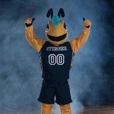 Yellow jacket mascot excitedly raising arms on basketball court.
