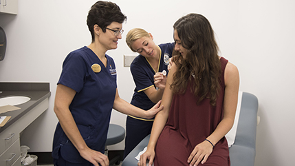 Cedarville student vaccinates another student, with a preceptor's assistance
