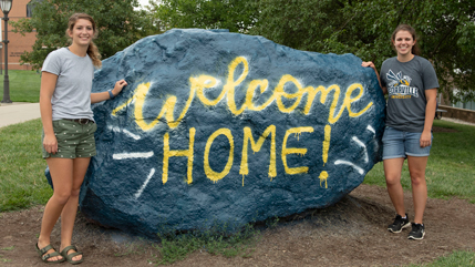 Two friends at the Rock with Welcome Home message spray painted