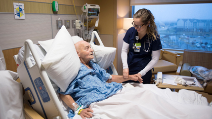 Nursing student working with patient in a hospital room