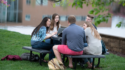 Students sitting at a picnic table next to Cedar Lake