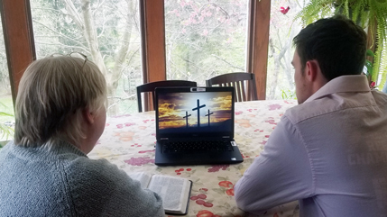 Mom and son looking at a computer screen with three crosses on a hill pictured