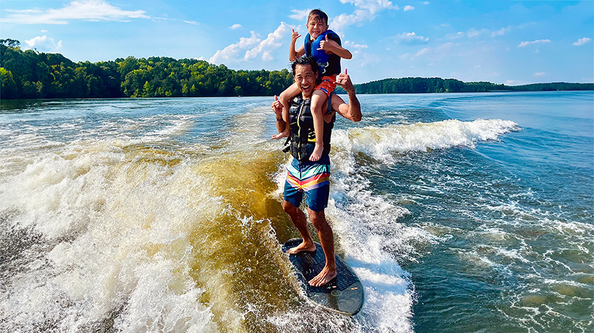 Jonathan Wu surfing with kid on his shoulders 858