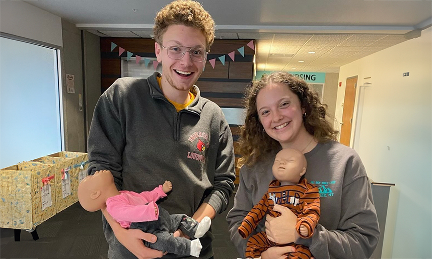 Nursing students hold new manikin babies at a program baby shower held to benefit a local crisis pregnancy resource center.