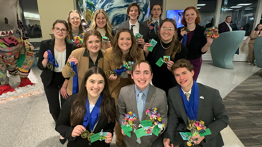 Cedarville University's forensics team smiling holding medals with blue ribbons.