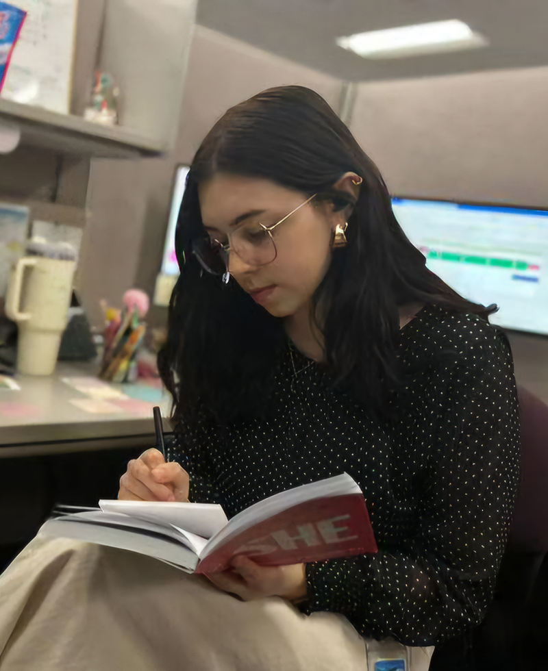 Chloe Hunt writing in a notepad while holding an open book.