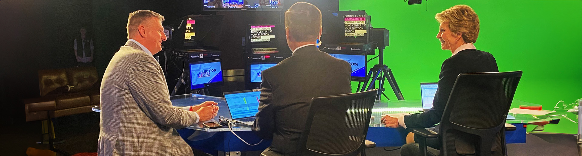 Dr. Mark Caleb Smith sitting behind news desk with news anchor giving an interview.