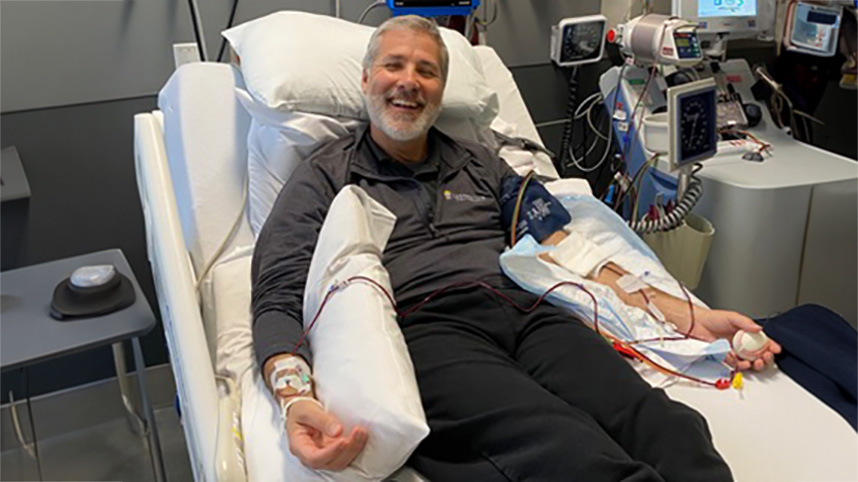 Dr. Will Smallwood smiling on hospital bed during his cancer treatment.