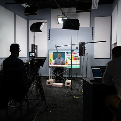 Media production studio with students recording an educational video under professional lighting.