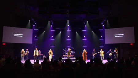 Chapel band playing on stage with words "Forever enough, always enough" on slideshow.