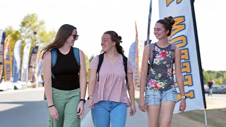 Three students walking in front of residence hall.