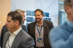 A man engages in conversation with others at a conference, showcasing networking and collaboration.