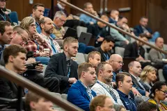 A packed auditorium filled with students and attendees, all focused on the speaker at the front.