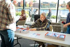 A man signs books at a table