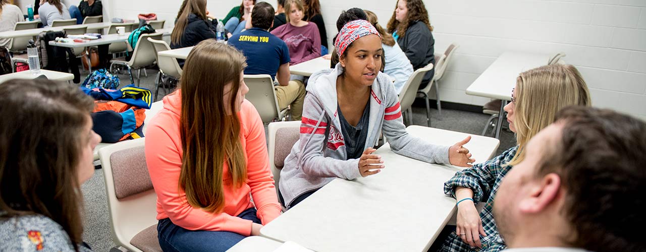 Female social work students discuss around a table