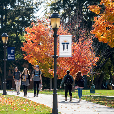 Students walk down a sidewalk in the fall