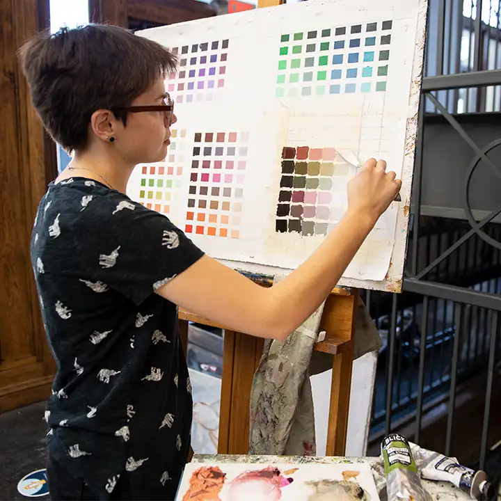 Person standing in front of painted color swatches.